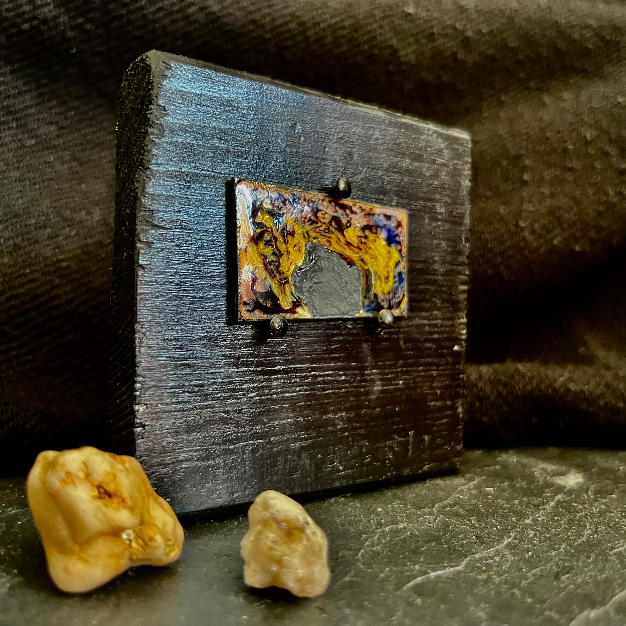 Fly Nest – original cloisonné enamel miniature on copper, side view on black frame with small stones from outside placed in the foreground. Handcrafted enamel art by A. Fraction.