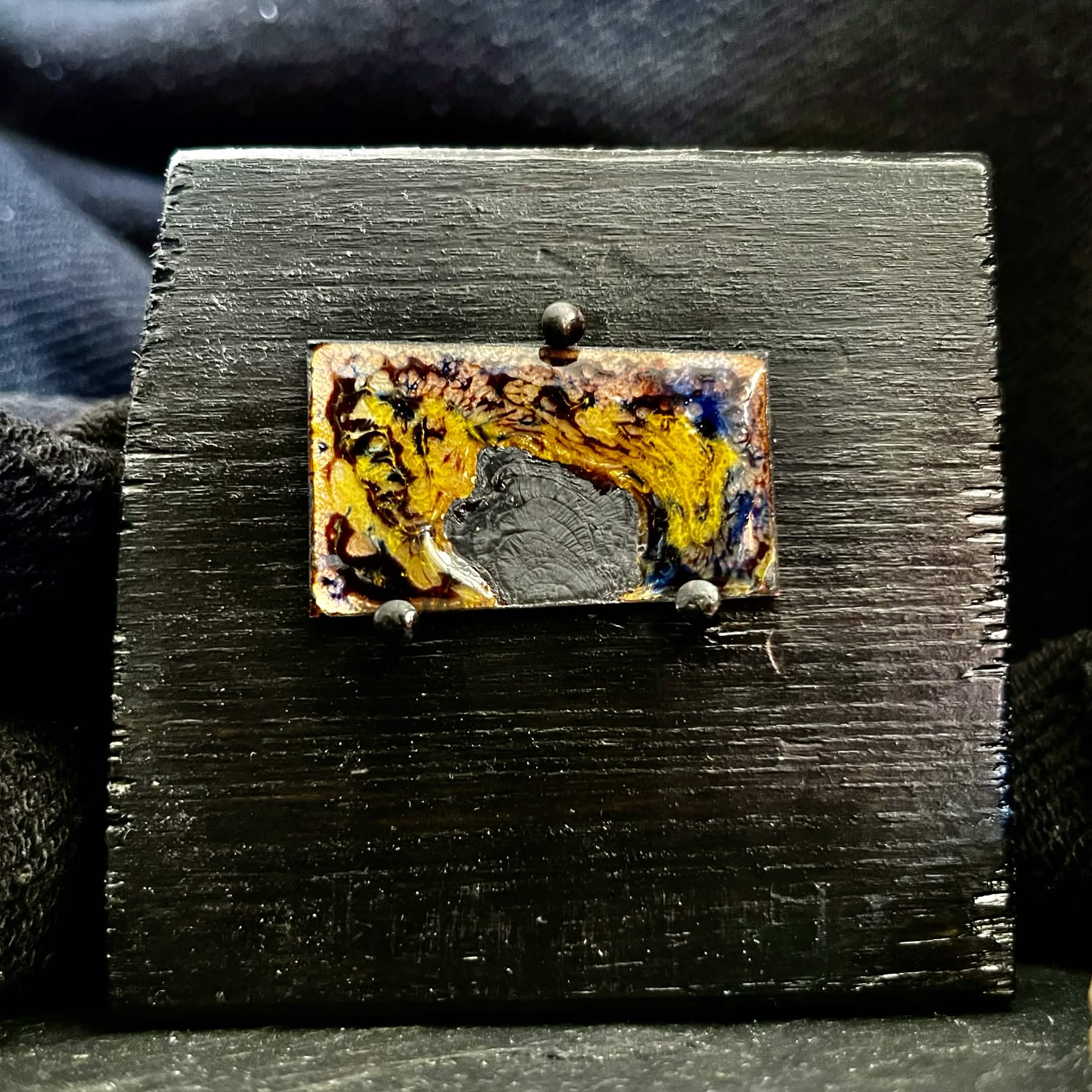 Fly Nest – original cloisonné enamel miniature on copper mounted on a black wooden frame, front view. Swirling brown, gold and blue enamel fired in the kiln. Handcrafted by A. Fraction.