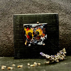 Baby Pigeons — vitreous enamel on copper miniature, 40 × 36 mm, fine silver cloisonné, kiln-fired. Warm amber, red and dark tones depicting two baby pigeons in a nest. Displayed on handmade black pine stand, 80 × 80 mm. House Zoo series by A. Fraction, Vilnius.