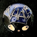 Whale Cat – original cloisonné enamel miniature on a round copper disc, front view on dark slate. A black cat with amber eyes and the blue sky reading "WHALE" in fine silver wire. House Zoo collection original artwork by A. Fraction.