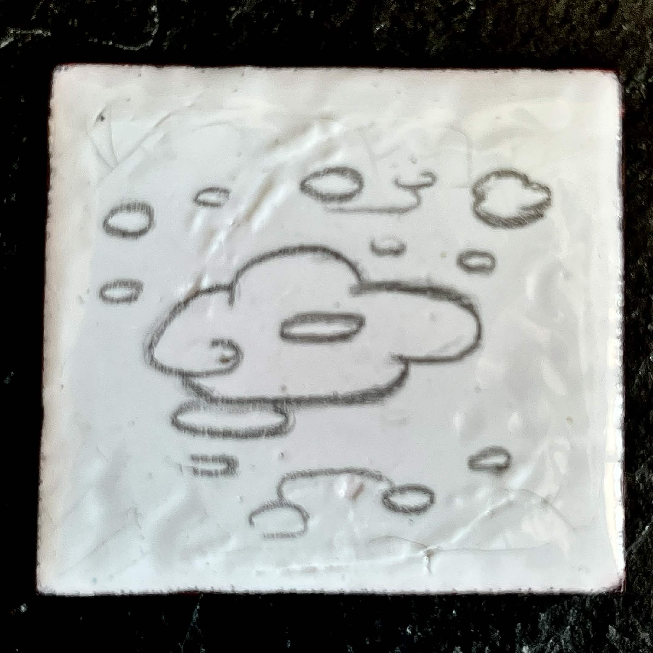 Close-up of Cloud — pencil-drawn cloud creature with a big nose on white vitreous enamel on copper, bumpy fired texture visible, by A. Fraction