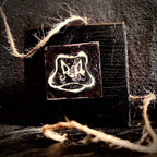 Cow's Hairy Nose champlevé enamel miniature mounted on handmade matte black pine stand, styled with natural rope on a dark textured surface, by A. Fraction